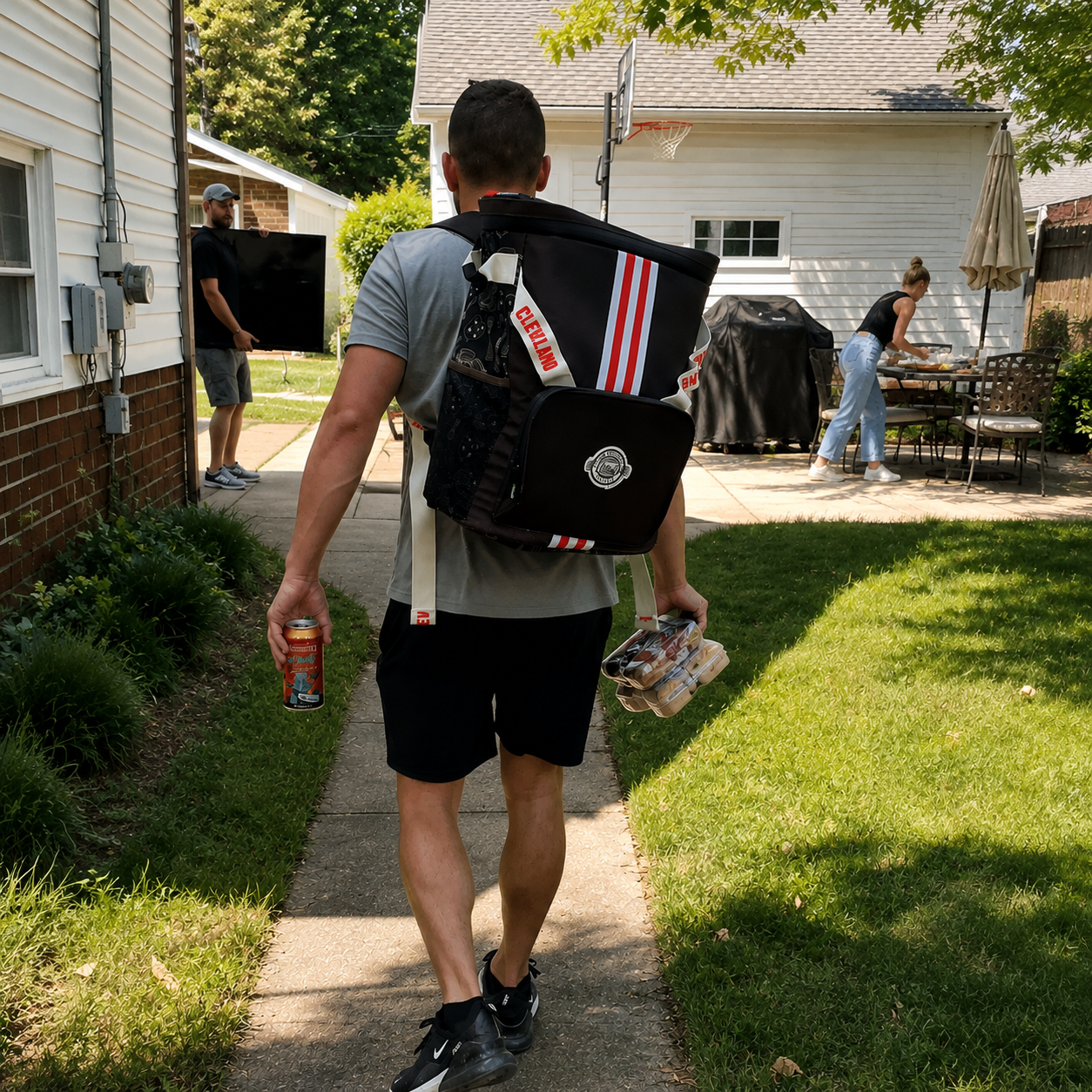 A-man-from-Cleveland-walks-down-a-backyard-pathway-wearing-a-large-Cleveland-backpack-style-messenger-bag-carrier-with-orange-and-white-stripes-and-holding-a-beverage-can-and-a-drink-in-his-hands.Ready-to-tailgate-for-the-Browns.-