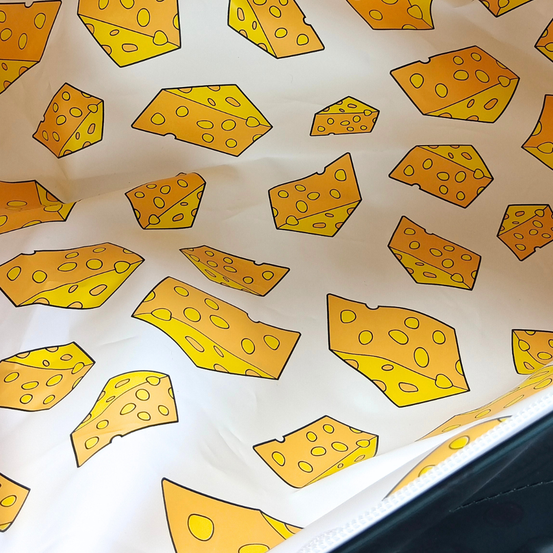 A-close-up-of-a-white-surface-printed-with-Green-Bay-Cheese-Head's-cheese-wedges-in-yellow-and-orange-tones,-with-a-dark-edge-visible-along-the-bottom-right.